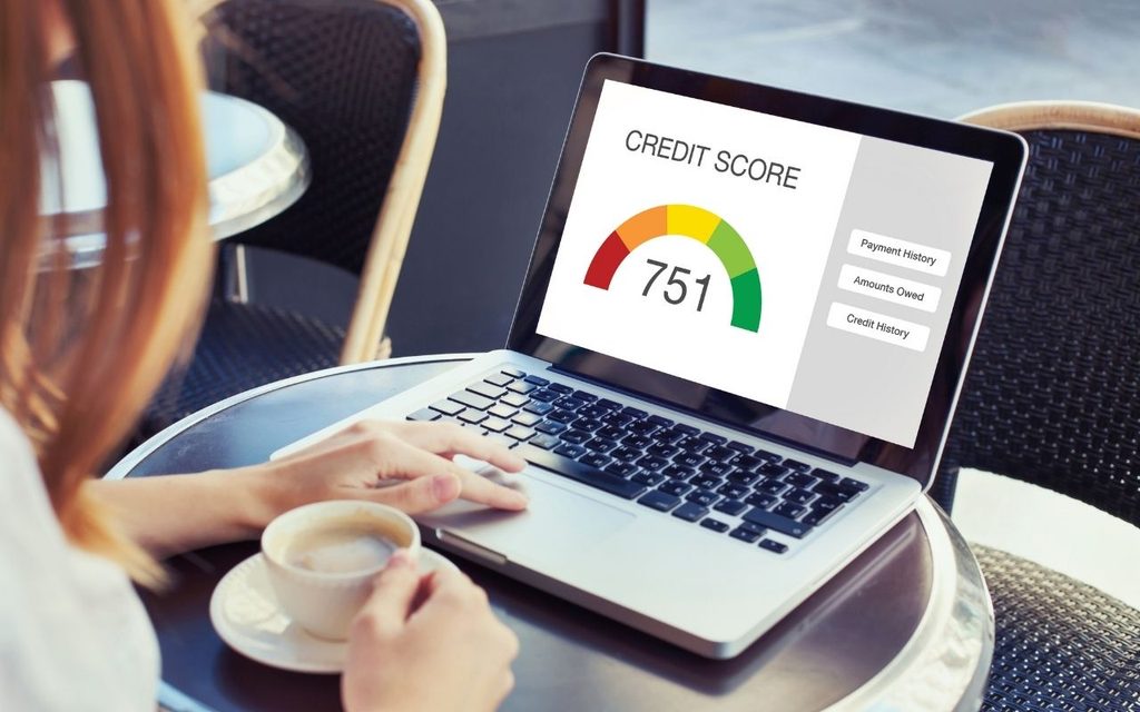 A woman looks at her credit score of 751 on a laptop.