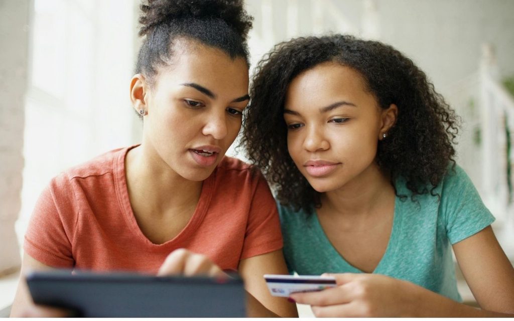One woman instructs another on using a credit card to establish good credit.